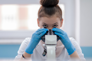 Image showing female student scientist looking through a microscope