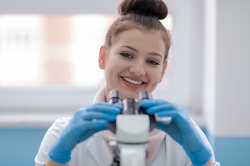 Image showing female student scientist looking through a microscope