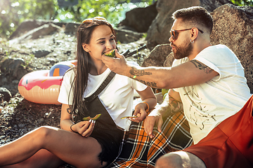 Image showing Young couple having picnic at riverside in sunny day