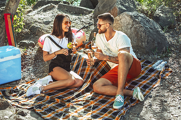 Image showing Young couple having picnic at riverside in sunny day