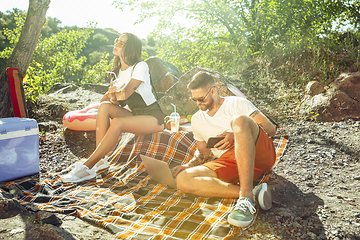 Image showing Young couple having picnic at riverside in sunny day