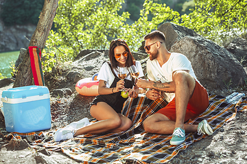 Image showing Young couple having picnic at riverside in sunny day