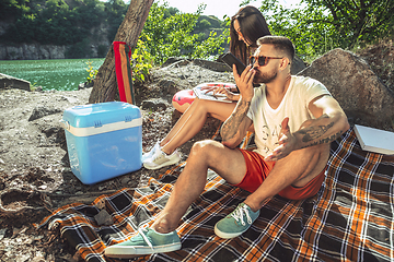 Image showing Young couple having picnic at riverside in sunny day