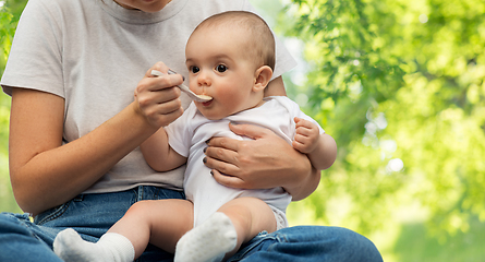 Image showing close up of mother with spoon feeding little baby