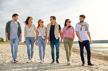 Image showing happy friends walking along summer beach