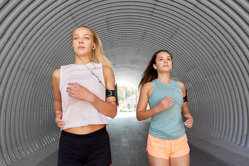 Image showing young women with earphones and smartphones running