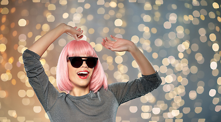 Image showing happy woman in pink wig and sunglasses dancing