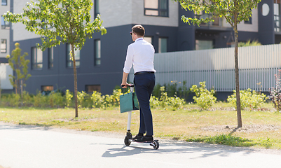 Image showing businessman with shopping bag riding scooter