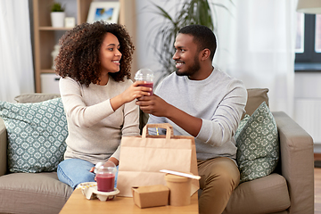 Image showing happy couple with takeaway food and drinks at home