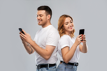 Image showing happy couple in white t-shirts with smartphones