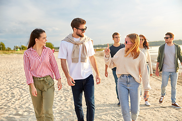 Image showing happy friends walking along summer beach