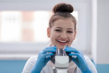 Image showing female student scientist looking through a microscope