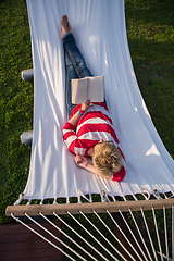 Image showing woman reading a book while relaxing on hammock