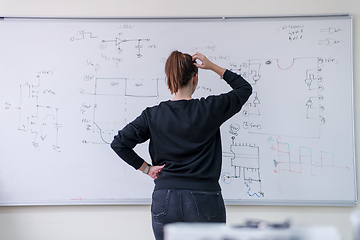 Image showing female student writing on board in classroom