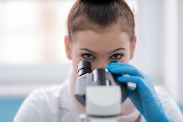 Image showing female student scientist looking through a microscope