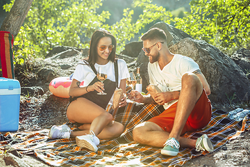 Image showing Young couple having picnic at riverside in sunny day