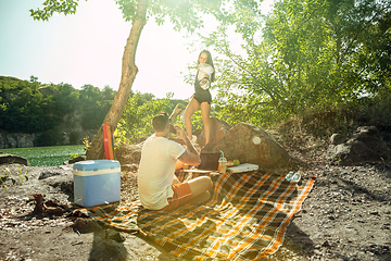 Image showing Young couple having picnic at riverside in sunny day