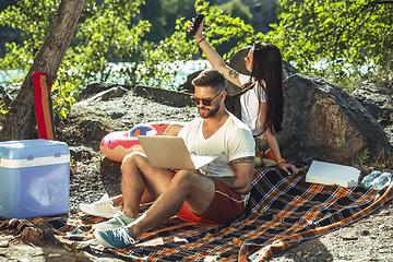 Image showing Young couple having picnic at riverside in sunny day