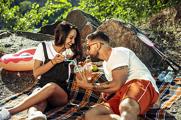 Image showing Young couple having picnic at riverside in sunny day