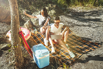 Image showing Young couple having picnic at riverside in sunny day