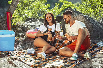 Image showing Young couple having picnic at riverside in sunny day