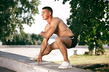 Image showing A male athlete doing workout on the city\'s street or park