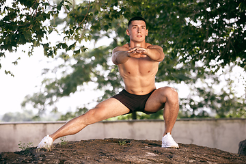 Image showing A male athlete doing workout on the city\'s street or park