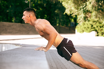 Image showing A male athlete doing workout on the city\'s street or park