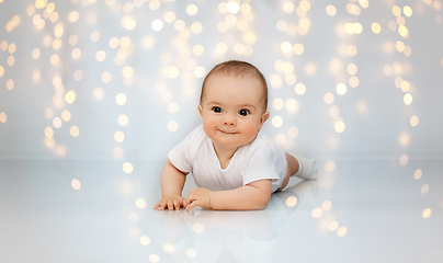 Image showing sweet little baby lying on floor over lights