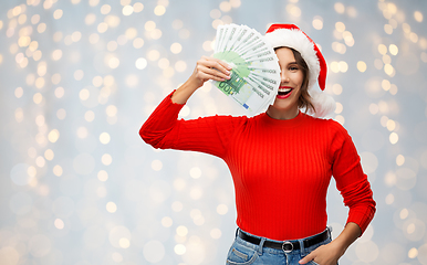 Image showing happy woman in santa hat with money on christmas