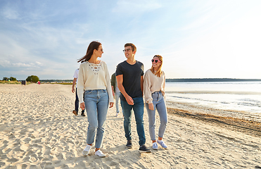 Image showing happy friends walking along summer beach