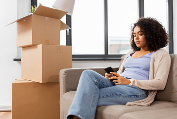 Image showing woman with smartphone and boxes moving to new home