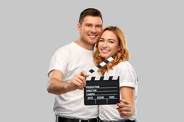 Image showing happy couple in white t-shirts with clapperboard