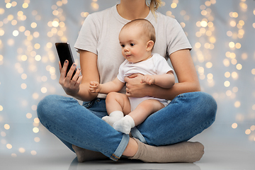 Image showing mother and baby looking at smartphone over lights