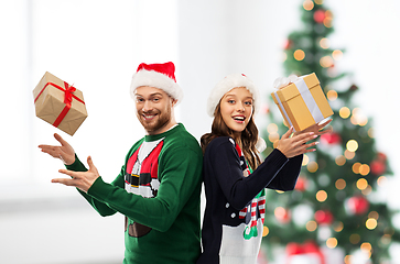 Image showing happy couple in christmas sweaters with gifts