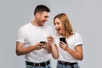 Image showing happy couple in white t-shirts with smartphones