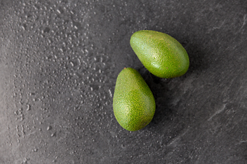 Image showing two avocados on wet slate stone background