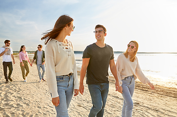 Image showing happy friends walking along summer beach