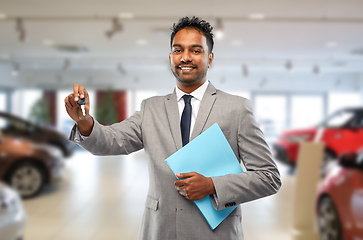 Image showing happy indian car dealer with car key at showroom