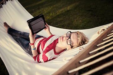 Image showing woman using a tablet computer while relaxing on hammock