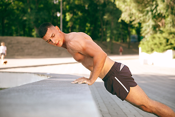 Image showing A male athlete doing workout on the city\'s street or park