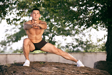 Image showing A male athlete doing workout on the city\'s street or park