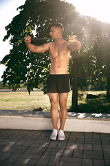 Image showing A male athlete doing workout on the city\'s street or park