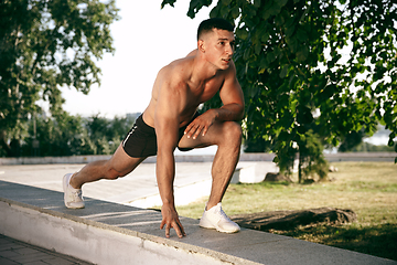 Image showing A male athlete doing workout on the city\'s street or park