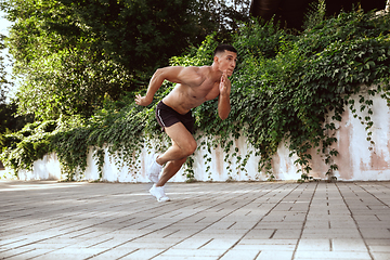 Image showing A male athlete doing workout on the city\'s street or park