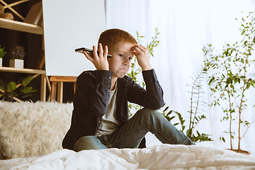 Image showing Little boy using different gadgets at home