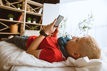 Image showing Little boy using different gadgets at home