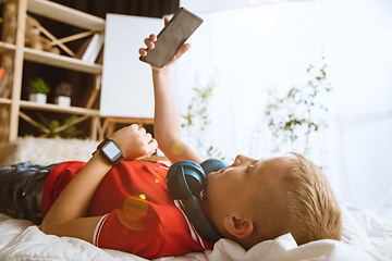 Image showing Little boy using different gadgets at home