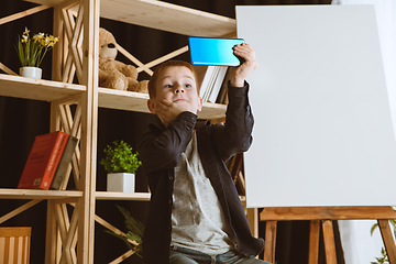 Image showing Little boy using different gadgets at home