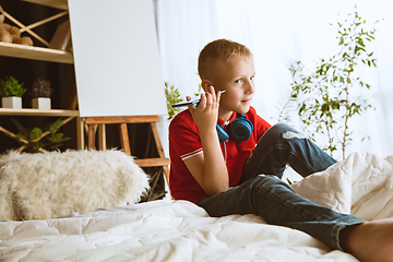 Image showing Little boy using different gadgets at home